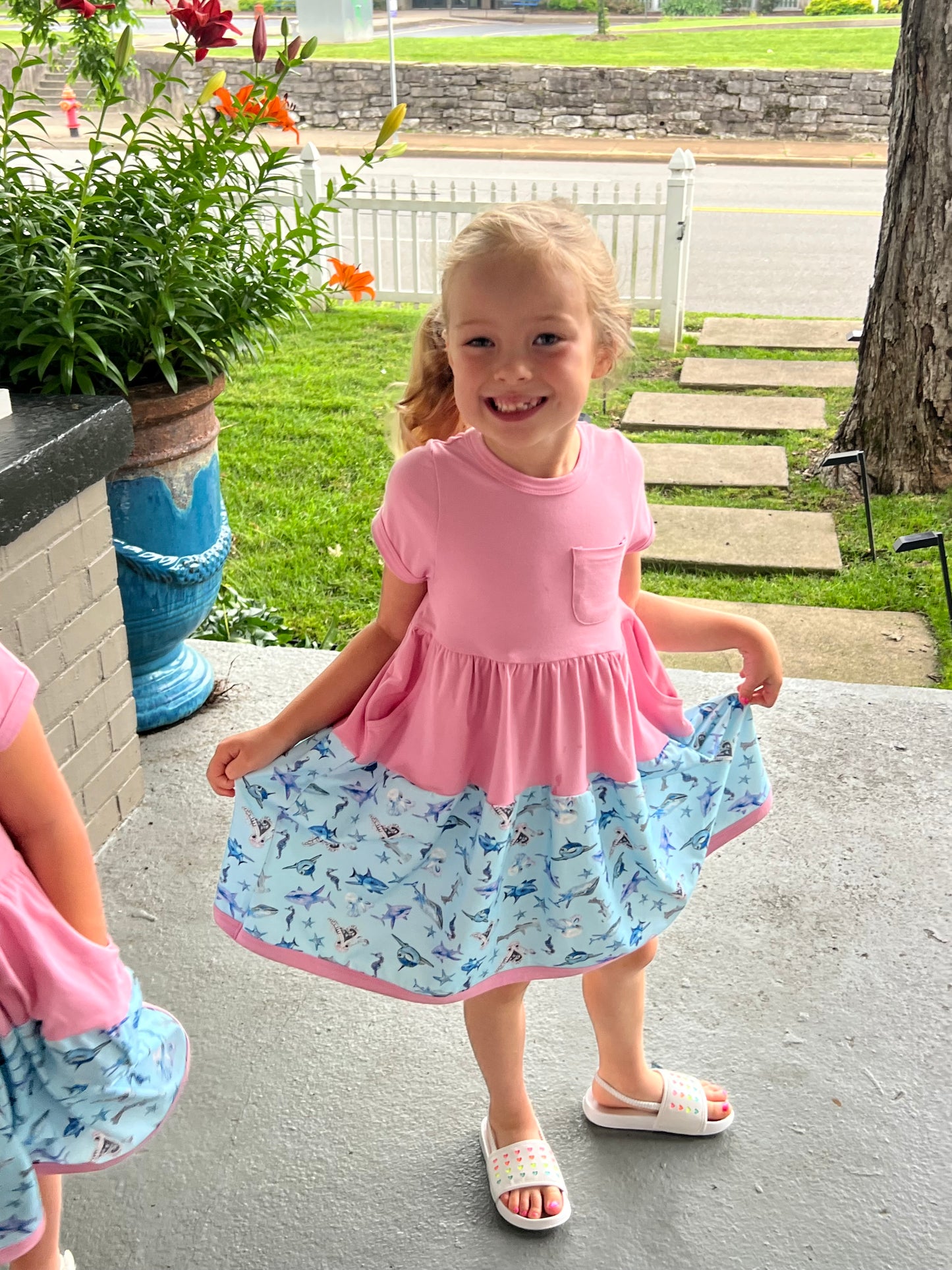 Girl wearing pink UnderTheSea dress with seahorses, sharks, whales, and starfish – designed for comfort and movement