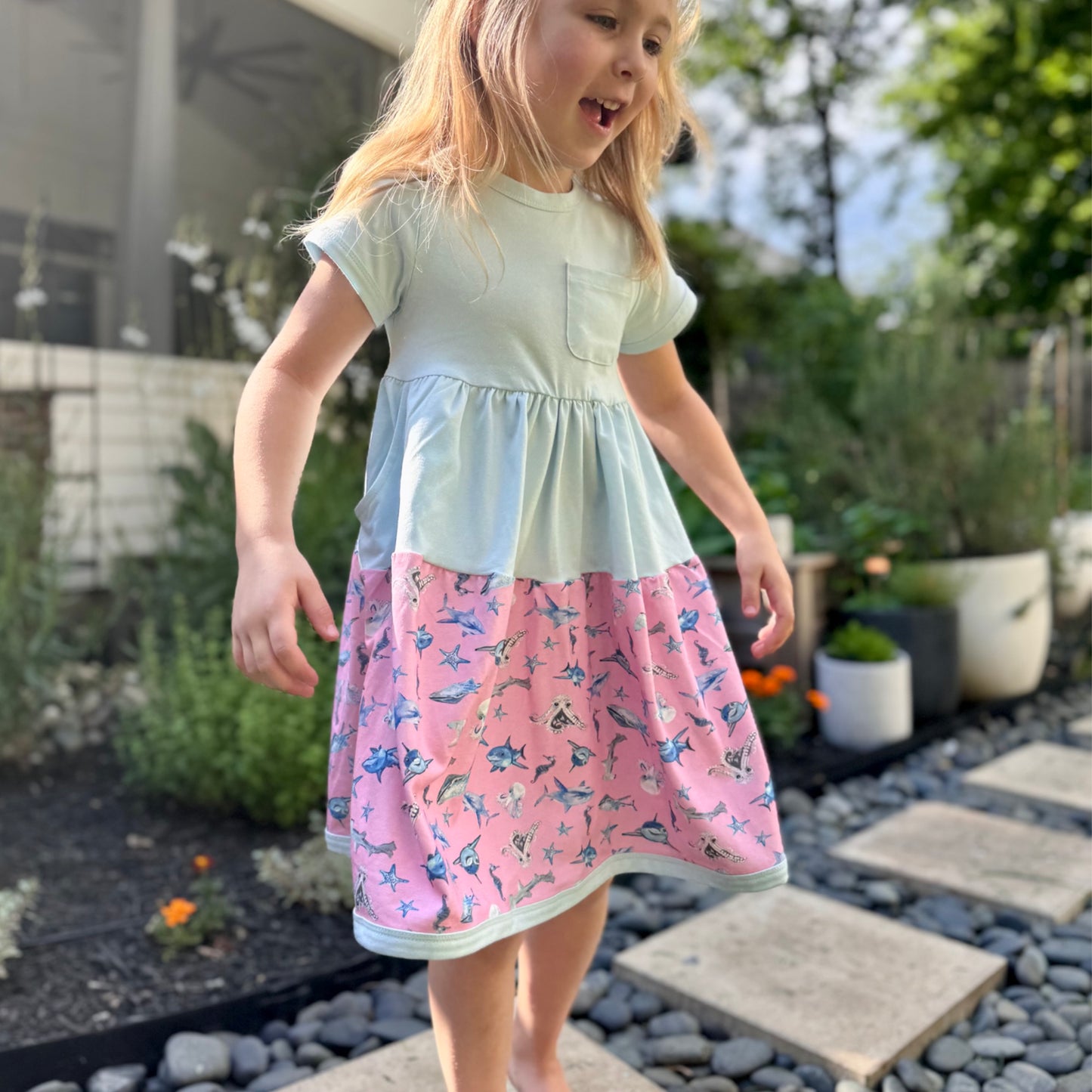 Little girl in blue short-sleeve shark dress smiling outdoors – breathable cotton dress with fun ocean creatures