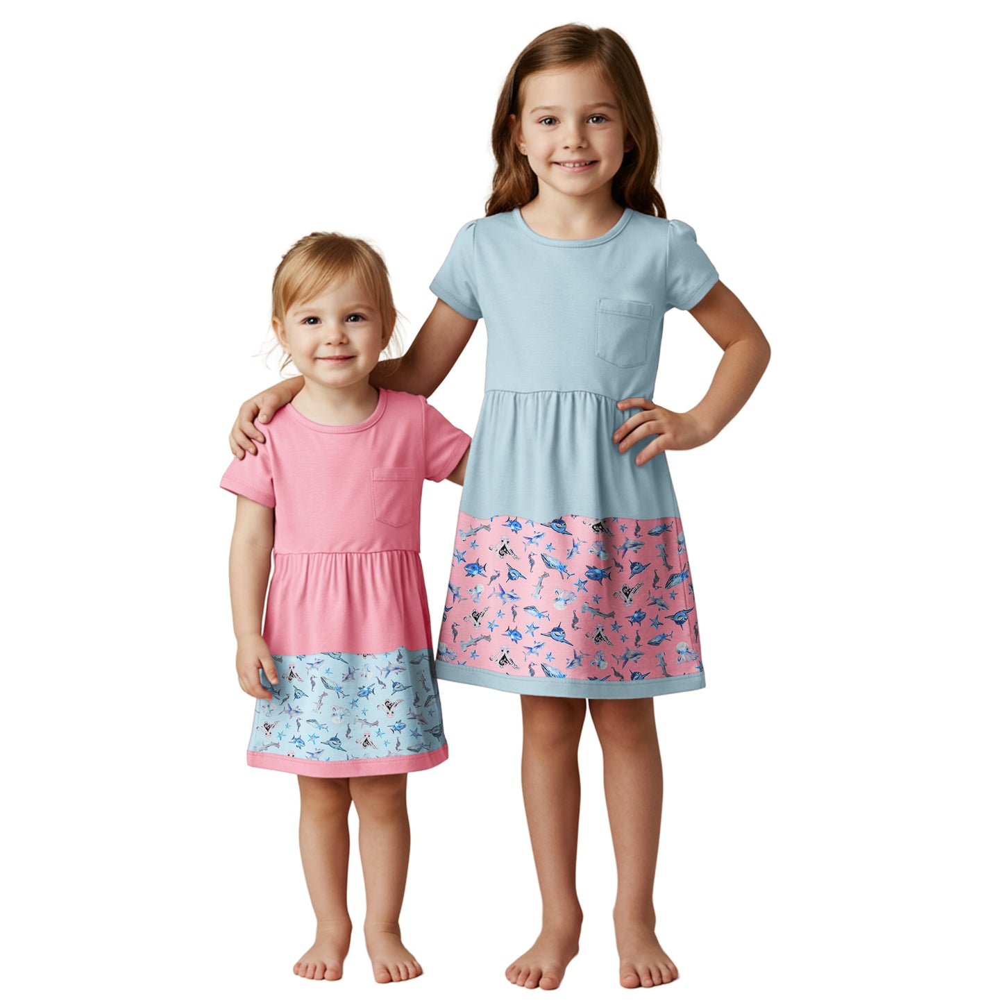 Two young girls wearing matching dresses with a white background