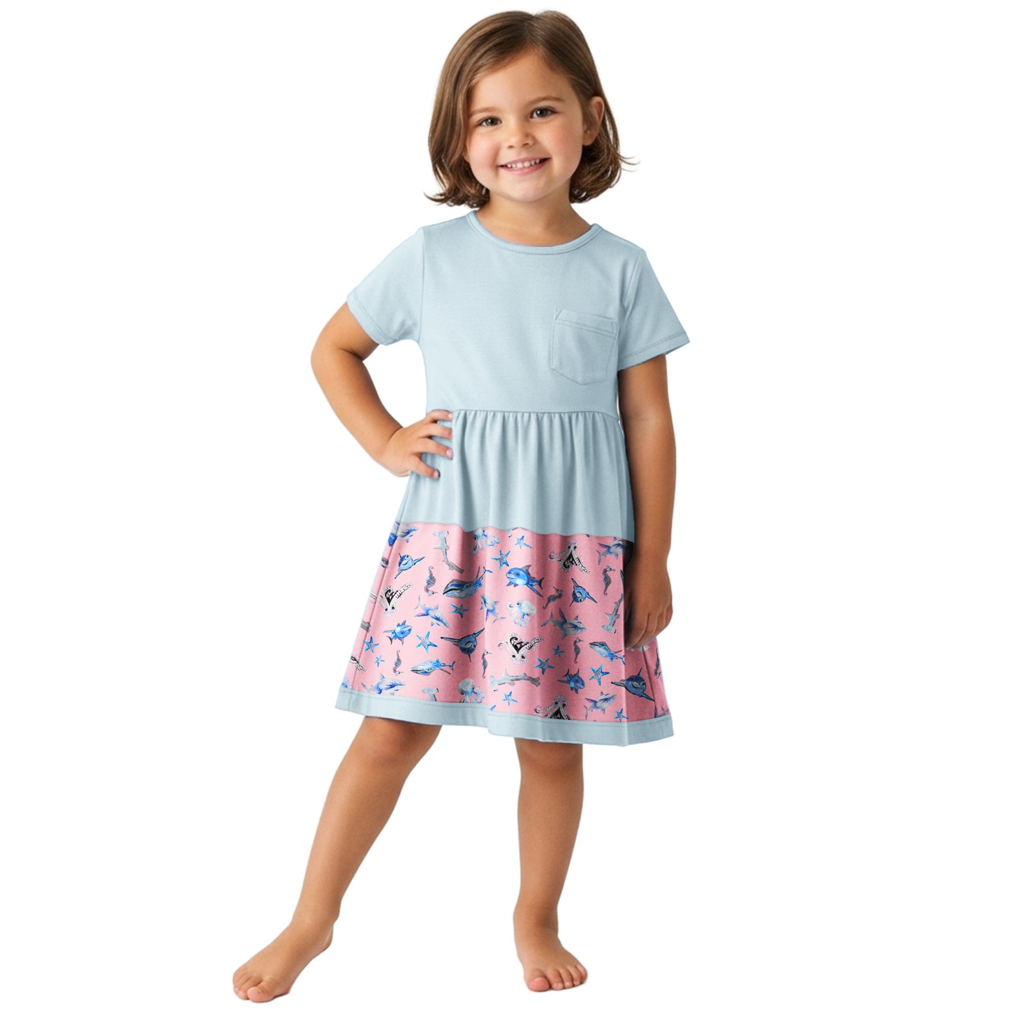 Young girl wearing a light blue dress with a pink skirt featuring animal prints on a white background