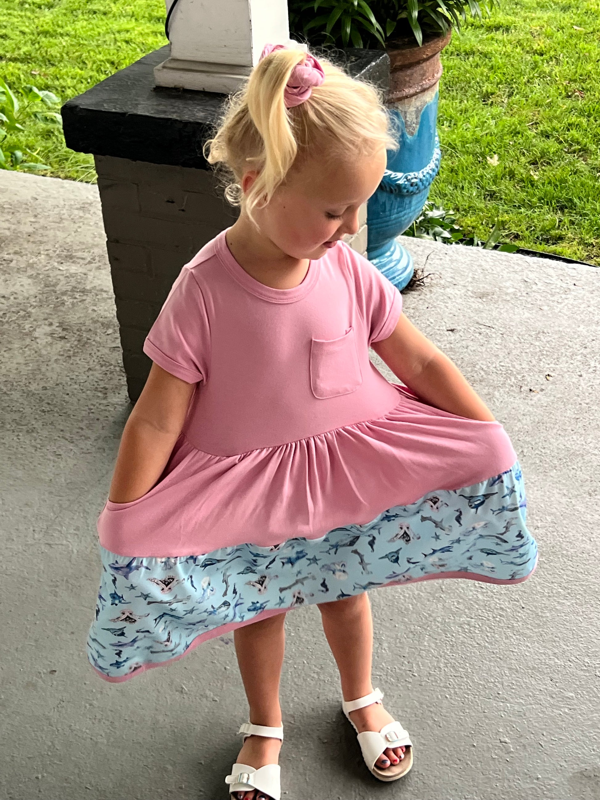 Preschool girl twirling in pink Sparky Shark dress with underwater print – soft cotton and scrunchie set for toddlers