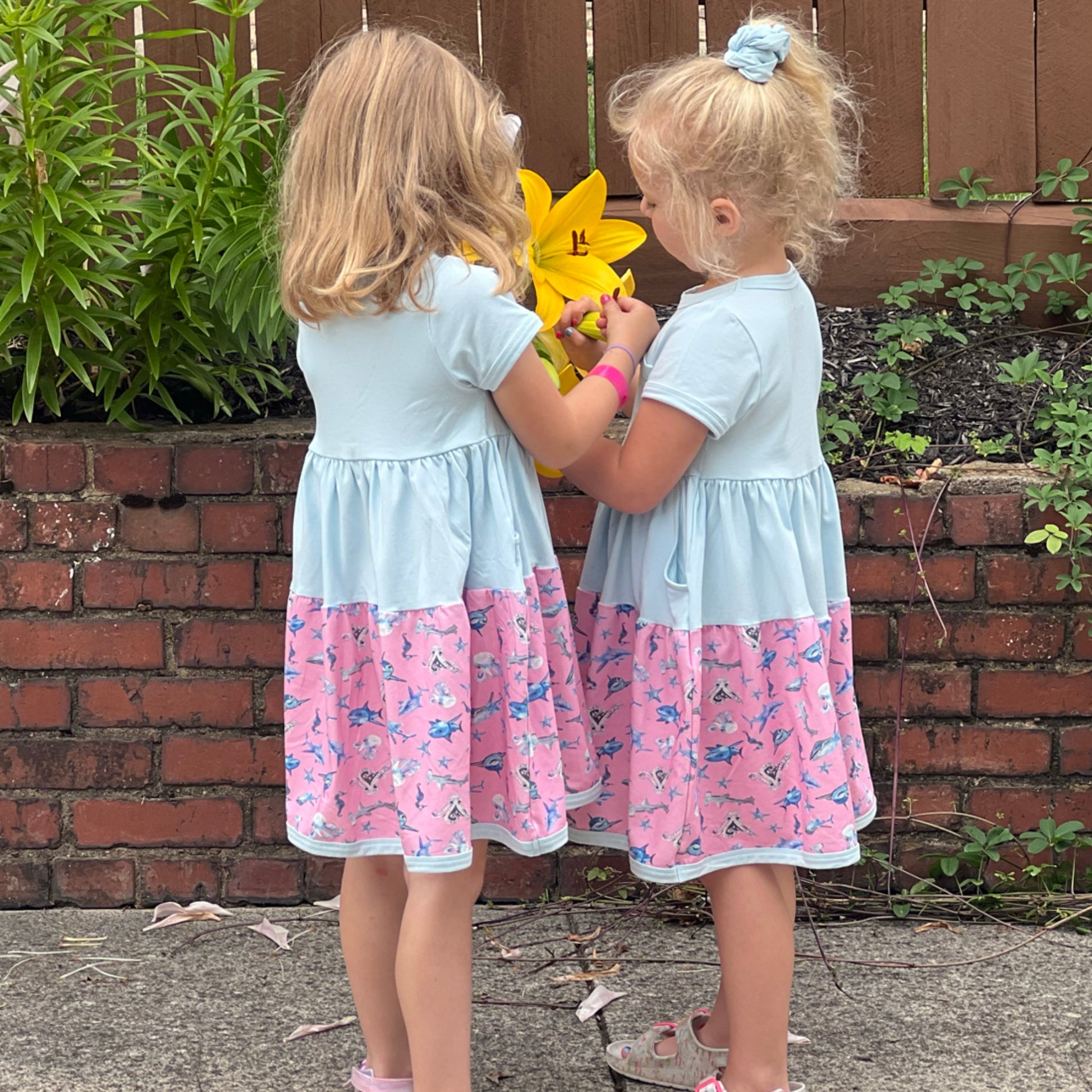 Two girls wearing Sparky Shark dresses in blue – ocean-themed twirl dresses with watercolor sea creatures
