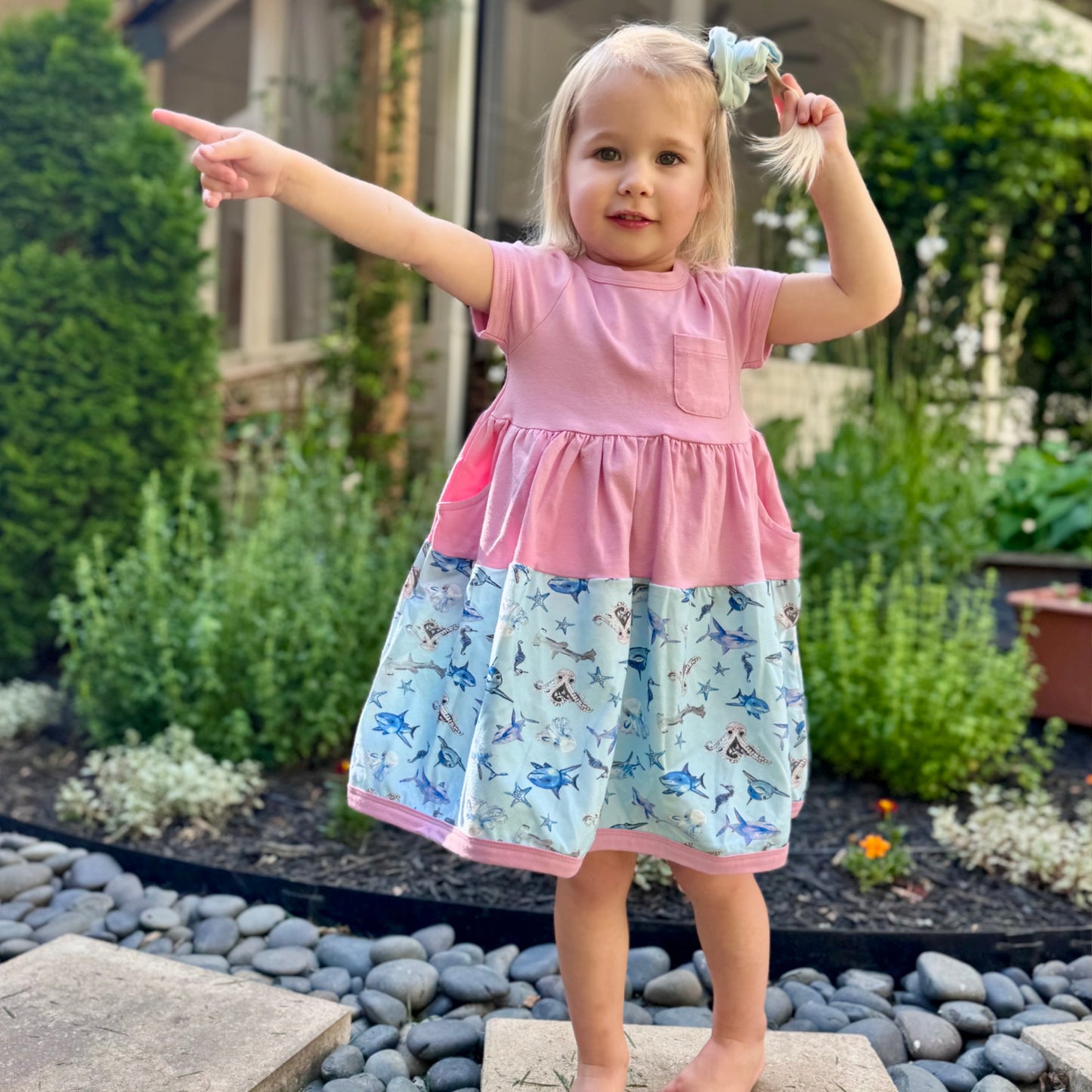 Girl wearing pink Sparky Shark dress with seahorses, sharks, whales – designed for comfort and movement