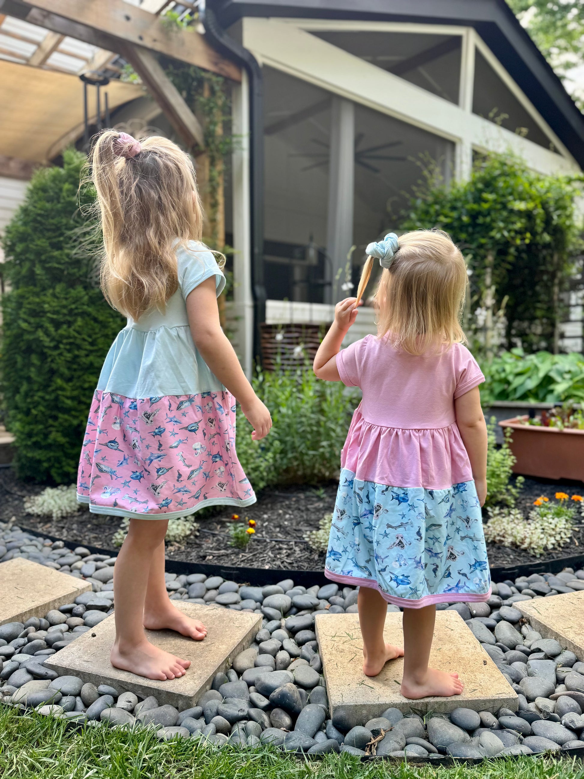 two girls wearing blue and pink shark twirl dresses standing outdoors soft sensory friendly summer outfits for kids